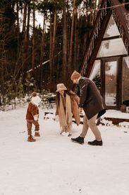 A Family Playing On Snow Covered Ground Near A House