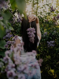 Young Woman With Lilac Flowers In Spring Garden