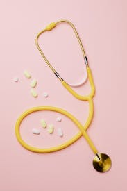 Yellow Stethoscope And Medicines On Pink Background