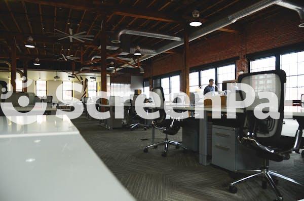 Two Men Having Conversation Next To Desk In Building