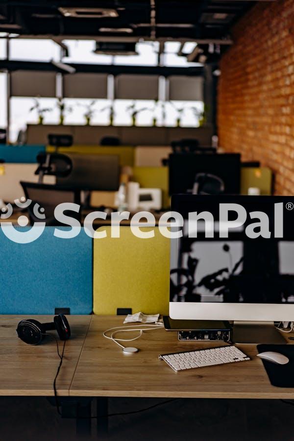 A Computer Monitor With Keyboard On A Wooden Table